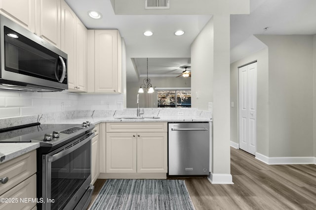 kitchen with white cabinetry, ceiling fan, appliances with stainless steel finishes, light stone counters, and sink