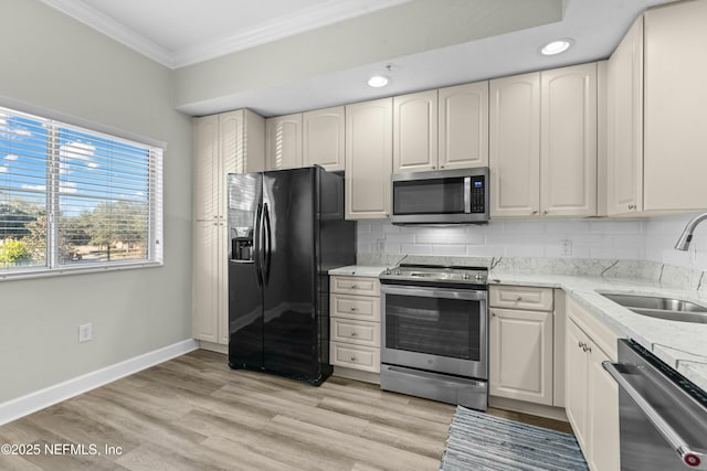 kitchen featuring light stone countertops, appliances with stainless steel finishes, sink, backsplash, and crown molding