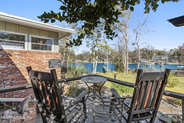 wooden terrace with a water view, a lawn, and fence