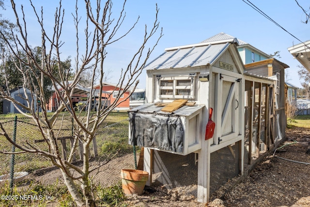 exterior space with metal roof, an outbuilding, exterior structure, and fence