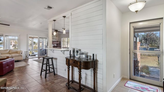 interior space with open floor plan, ceiling fan, a kitchen bar, and visible vents