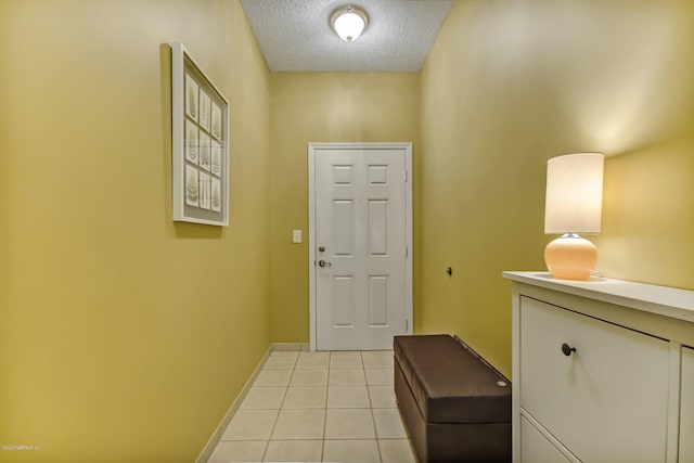 doorway to outside featuring light tile patterned flooring and a textured ceiling