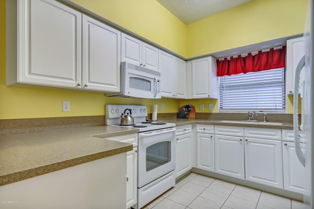 kitchen with light tile patterned floors, sink, white appliances, and white cabinets