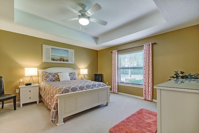 carpeted bedroom featuring ceiling fan, a textured ceiling, and a raised ceiling