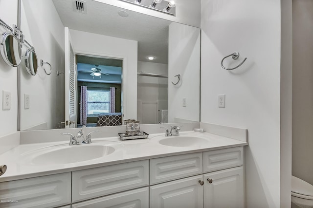 bathroom with ceiling fan, vanity, an enclosed shower, and toilet