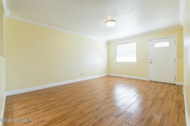 foyer featuring a textured ceiling, crown molding, and light wood-type flooring