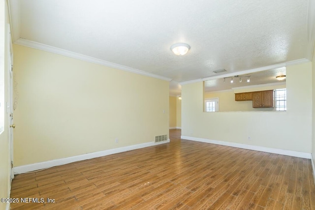 unfurnished room featuring hardwood / wood-style flooring, ornamental molding, and rail lighting