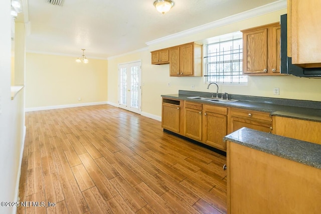 kitchen with french doors, an inviting chandelier, sink, light hardwood / wood-style flooring, and crown molding