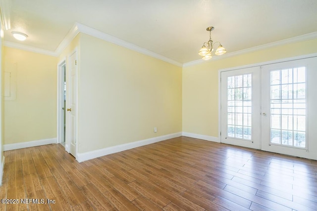 empty room featuring ornamental molding, a chandelier, and wood-type flooring