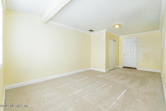 empty room featuring carpet flooring, beam ceiling, and ornamental molding