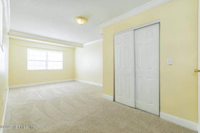 unfurnished bedroom with light colored carpet, a closet, and crown molding