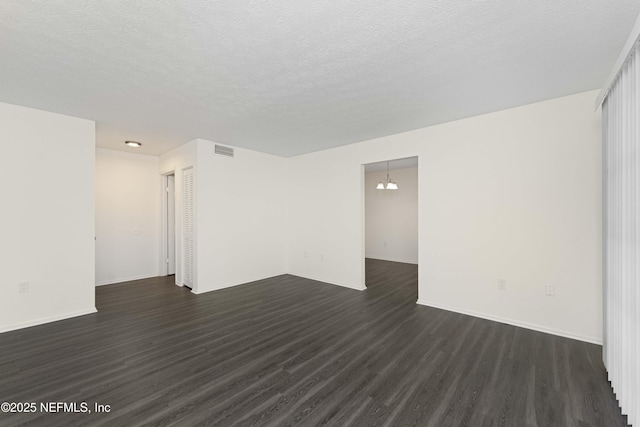 spare room featuring a textured ceiling, a chandelier, and dark hardwood / wood-style floors