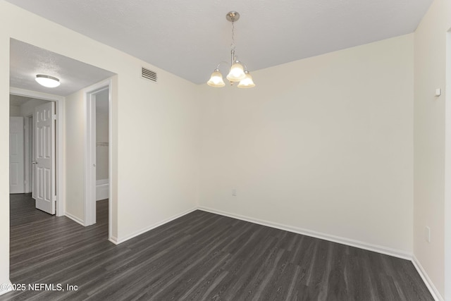 unfurnished room with a textured ceiling, dark hardwood / wood-style floors, and a notable chandelier