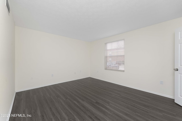 spare room featuring dark hardwood / wood-style floors and a textured ceiling