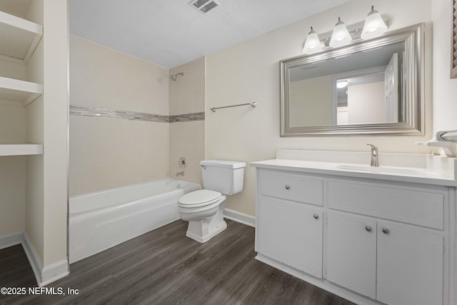 full bathroom featuring hardwood / wood-style floors, a textured ceiling, tiled shower / bath combo, vanity, and toilet