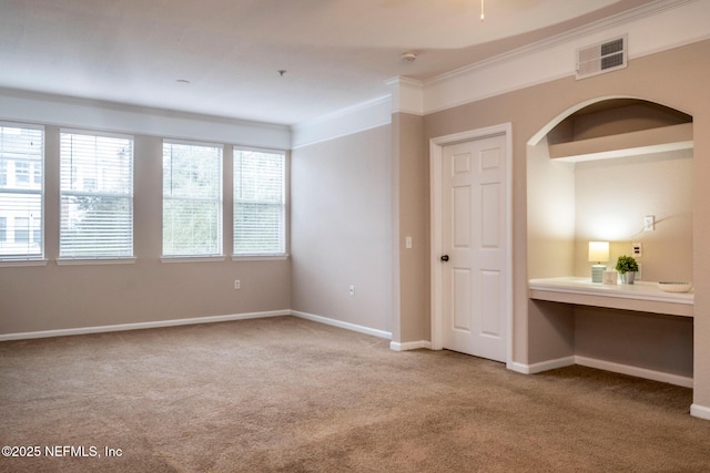 unfurnished bedroom with visible vents, arched walkways, carpet, crown molding, and baseboards