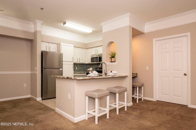 kitchen with appliances with stainless steel finishes, light carpet, decorative backsplash, and dark stone countertops