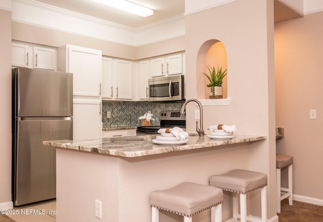 kitchen with decorative backsplash, white cabinets, a peninsula, and stainless steel appliances