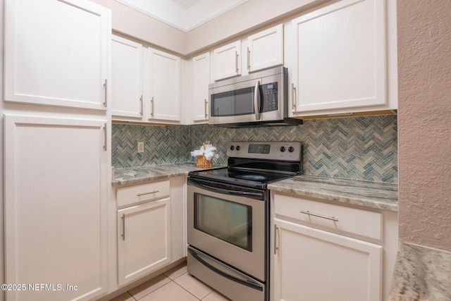 kitchen featuring light tile patterned floors, backsplash, appliances with stainless steel finishes, light stone countertops, and white cabinets