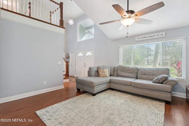 living room with a high ceiling, plenty of natural light, hardwood / wood-style flooring, and ceiling fan