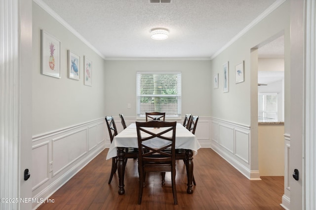 dining area featuring a textured ceiling, dark hardwood / wood-style flooring, and crown molding