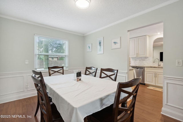 dining space with sink, a textured ceiling, dark hardwood / wood-style flooring, and ornamental molding