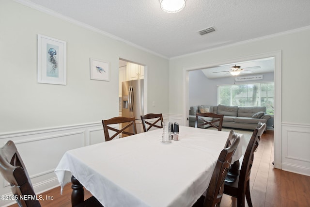 dining room with a textured ceiling, dark hardwood / wood-style flooring, and ornamental molding