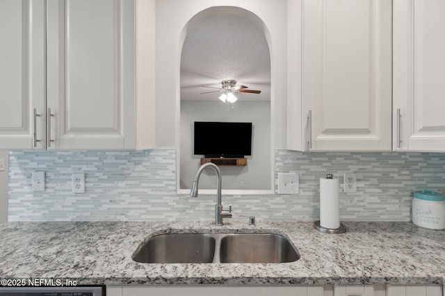 kitchen featuring white cabinetry, tasteful backsplash, ceiling fan, sink, and light stone counters