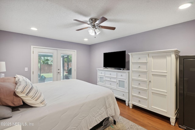 bedroom featuring ceiling fan, access to exterior, light hardwood / wood-style flooring, a textured ceiling, and french doors