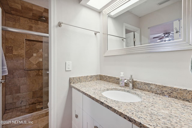 bathroom with vanity, ceiling fan, and walk in shower