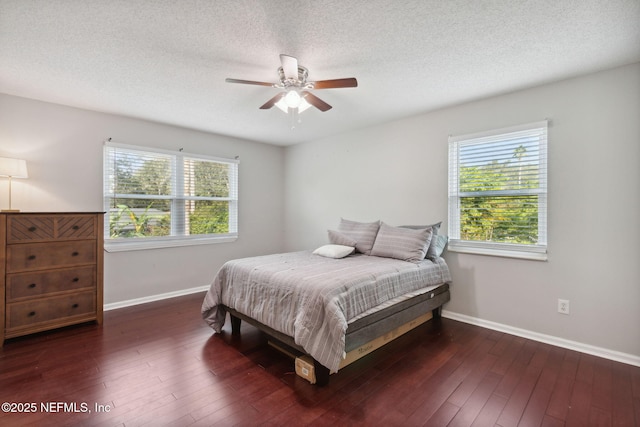 bedroom with ceiling fan, dark hardwood / wood-style flooring, and multiple windows