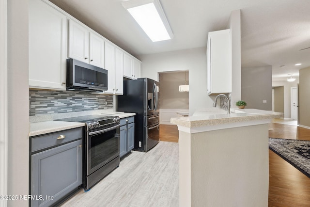 kitchen with stainless steel appliances, gray cabinetry, white cabinets, and kitchen peninsula