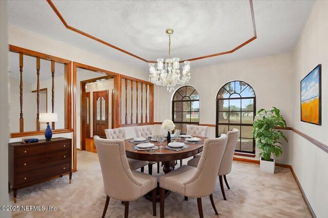 carpeted dining space with an inviting chandelier, a raised ceiling, and a textured ceiling