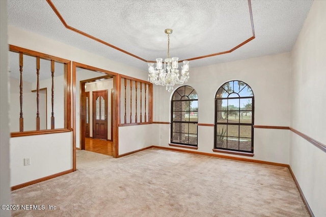 unfurnished room featuring light colored carpet, a textured ceiling, a chandelier, and a tray ceiling