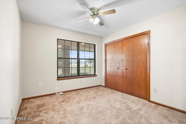 unfurnished bedroom featuring ceiling fan, light colored carpet, a closet, and a textured ceiling