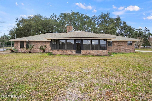 rear view of house with a yard and a sunroom