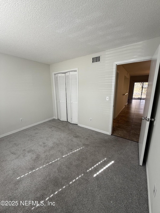 unfurnished bedroom with carpet floors, a textured ceiling, and a closet