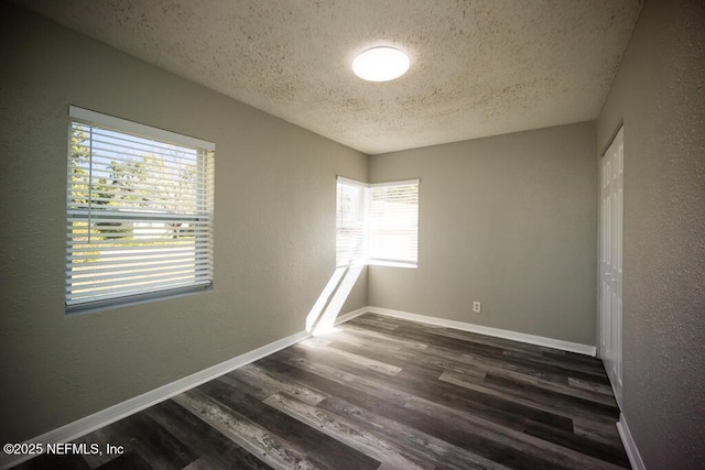 empty room featuring a textured ceiling and dark hardwood / wood-style flooring