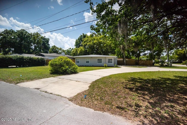 single story home featuring a front lawn, fence, and curved driveway