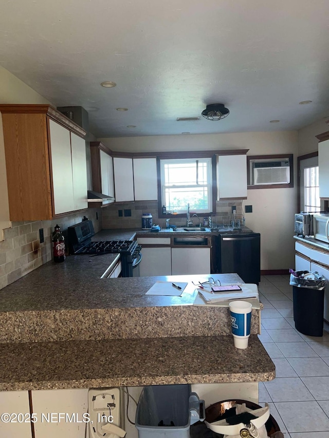 kitchen featuring an AC wall unit, decorative backsplash, white cabinets, and stainless steel range with gas cooktop