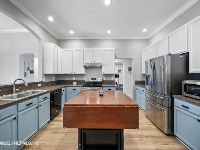 kitchen with appliances with stainless steel finishes, white cabinetry, sink, blue cabinetry, and a textured ceiling