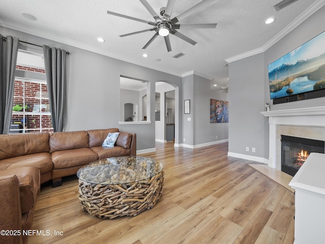 living room with crown molding, ceiling fan, a textured ceiling, and light hardwood / wood-style flooring