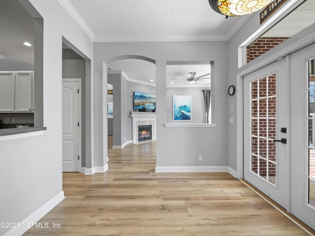 interior space featuring crown molding, light hardwood / wood-style floors, and a textured ceiling