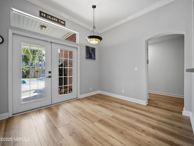 unfurnished dining area with french doors, ornamental molding, hardwood / wood-style floors, and a textured ceiling