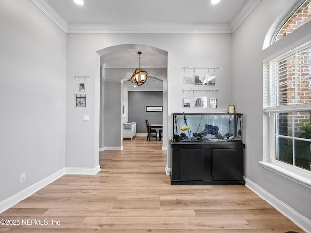 hallway featuring light hardwood / wood-style flooring, ornamental molding, and a chandelier