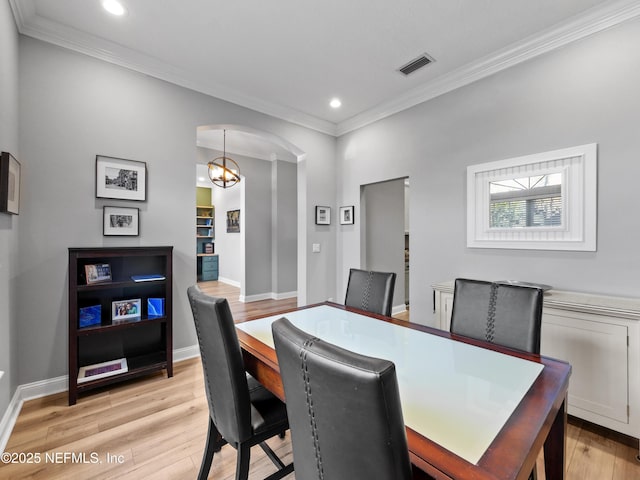 dining area featuring ornamental molding, a notable chandelier, and light hardwood / wood-style floors