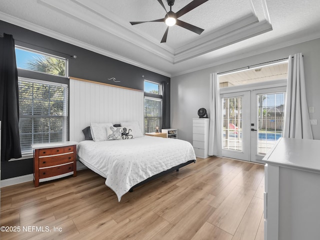 bedroom with french doors, ornamental molding, a tray ceiling, ceiling fan, and access to exterior