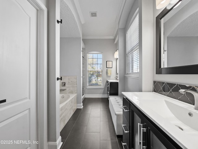 bathroom featuring crown molding, vanity, tiled bath, a textured ceiling, and tile patterned floors