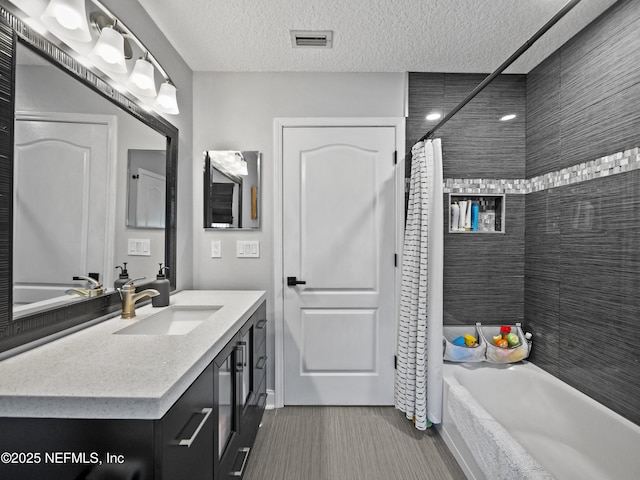 bathroom featuring shower / bath combination with curtain, vanity, and a textured ceiling