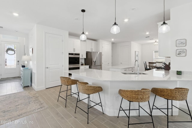 kitchen featuring kitchen peninsula, sink, white cabinetry, hanging light fixtures, and stainless steel appliances